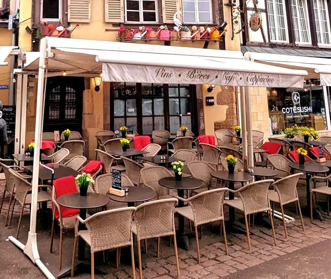La terrasse du Stam, fauteuils en rotin et plaids rouges